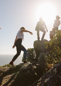 95742325 - group of friends on a mountain. young people on mountain hike on a summer day. men and women climbing rocks.